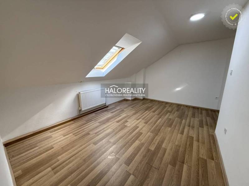Attic studio with a window, white walls, and a floor with a wooden decor.