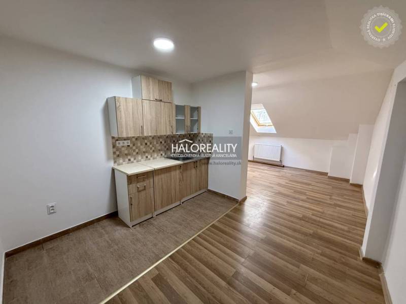 A studio apartment with a wooden floor and a kitchenette.