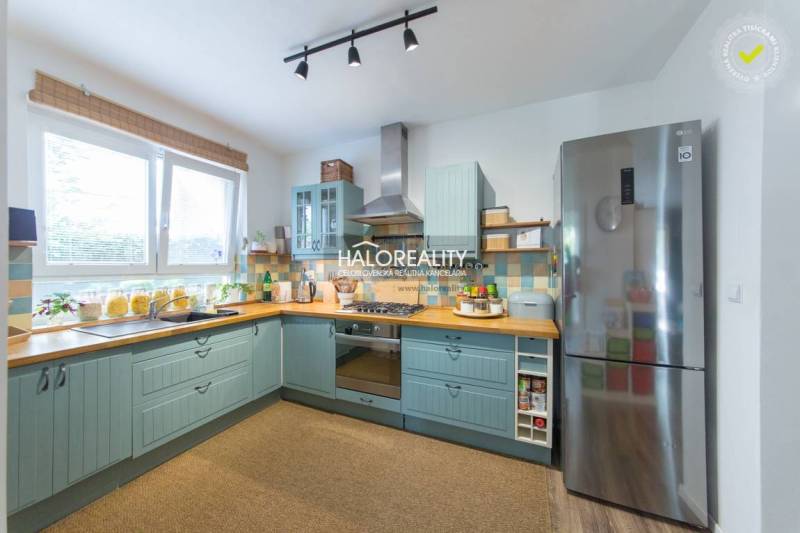 A spacious kitchen with light blue cabinets and stainless steel appliances in a 3-room apartment.