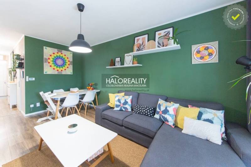 Living room with a sofa, dining table, and wooden decor flooring in a three-room apartment.