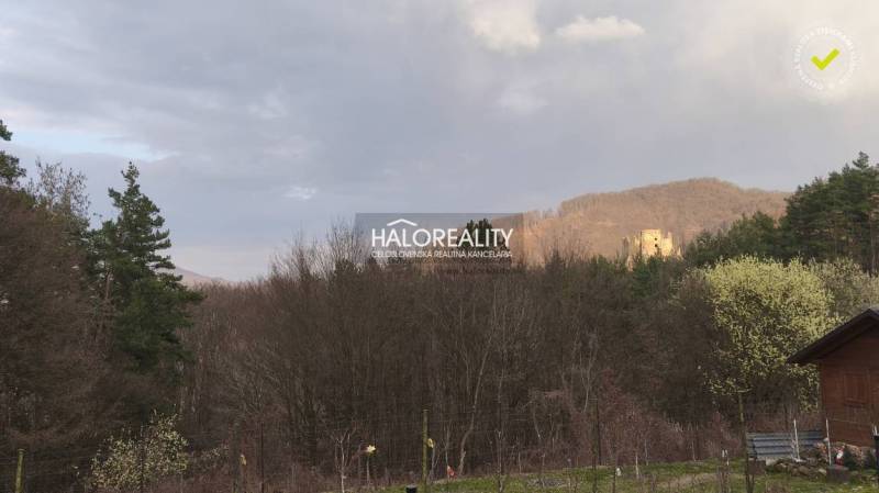 The landscape in Ladomerská Vieska with a view of wooded hills and an old castle.