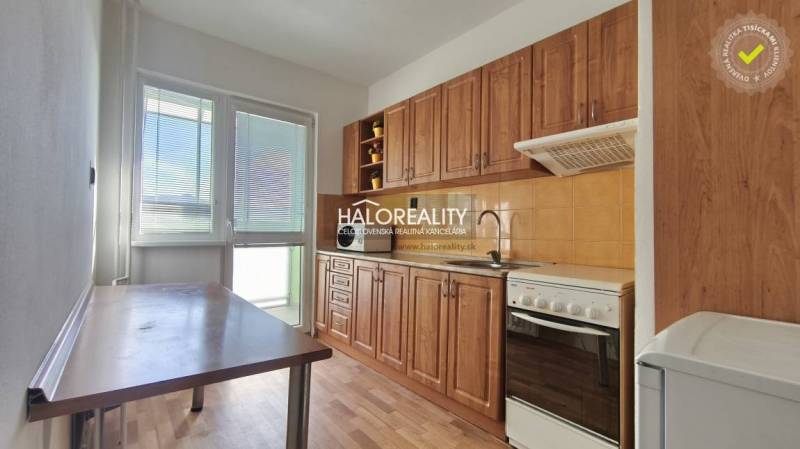 A kitchen in a 3-room apartment with a wooden decor floor, light walls, and a balcony.