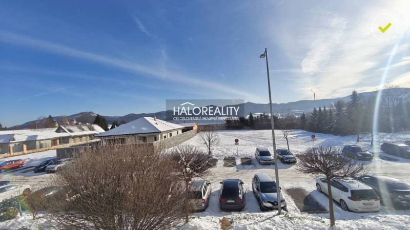 Snowy landscape and cars parked near a building in Žiar nad Hronom.