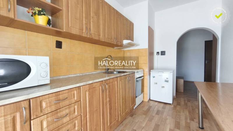 A kitchen in a 3-room apartment with a wooden decor floor and wooden cabinets.