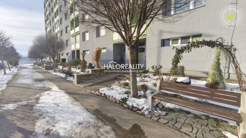 Apartment building with a snowy sidewalk and bench in Žiar nad Hronom near a 3-room apartment.
