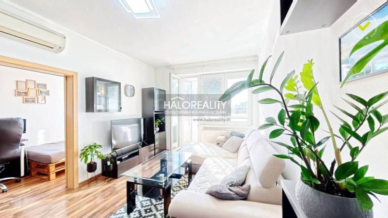 Living room in a 3-room apartment with a wooden decor floor and a white sofa.
