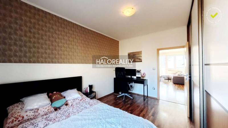 A bedroom in a three-room apartment with a wooden decor floor and a desk.