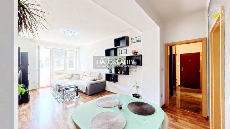 Living room of a three-room apartment with a wooden decor floor and light seating.