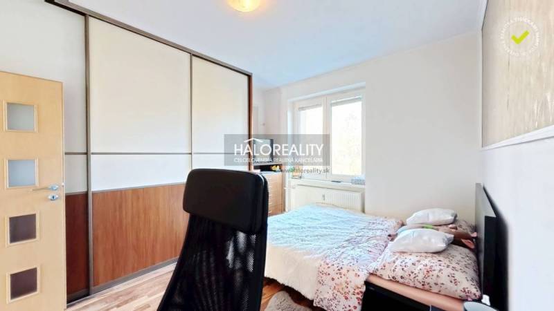 Bedroom with a large wardrobe, wood-decorated flooring, and an office chair in a 3-room apartment.