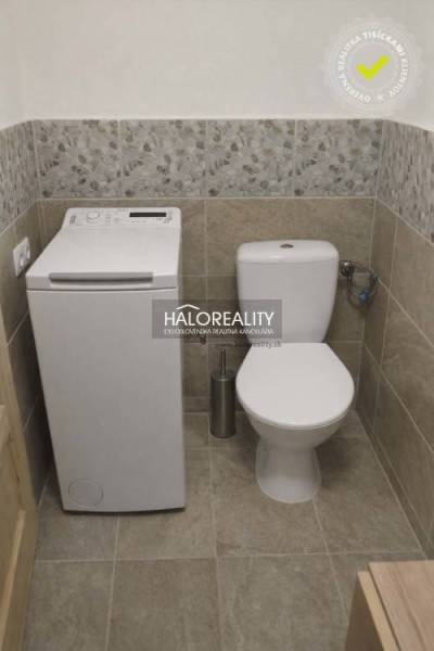 Toilet with a washing machine in the bathroom of a family house, stone-patterned tiles.