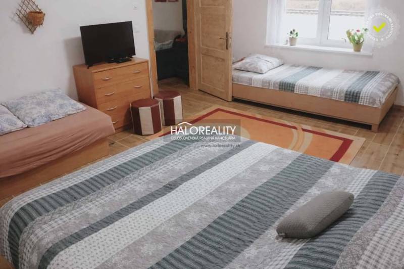 Interior of a family house with beds, a television, and a floor with a wooden decor.