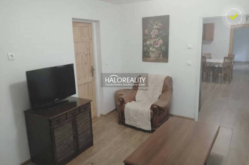 Living room of a family house with a television, an armchair, and a wooden decor floor.
