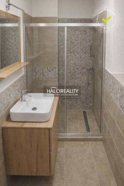 Bathroom in a family house with a sink, shower corner, and tiles with a wooden decor.