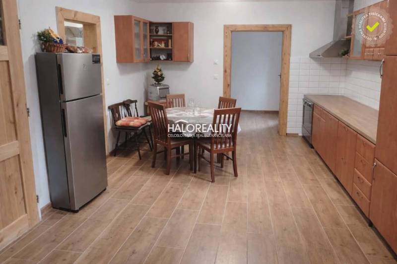 A kitchen in a family house with a dining table and a wooden-patterned floor.