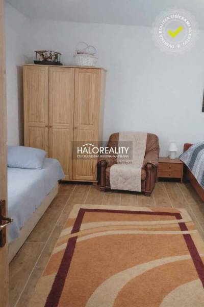 Bedroom in a family house with a wood-patterned floor, beds, and a chair.