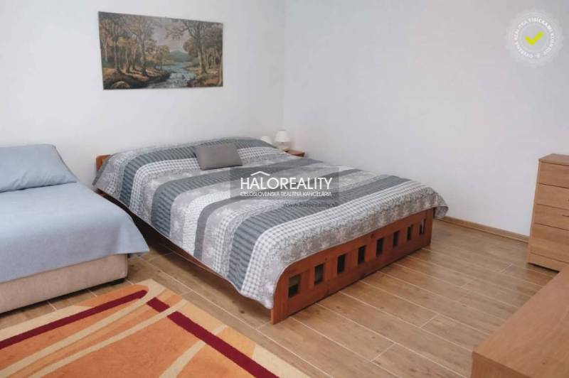 A bedroom with a bed, a sofa, and a wooden decor floor in a family house.