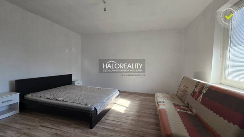Bedroom with a bed, sofa, and wooden decor flooring in a family house.