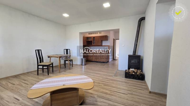 Interior of a family house with a stove, wooden decor flooring, and simple furniture.