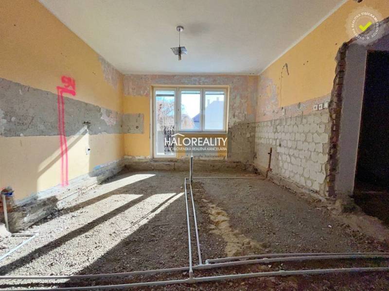 The interior of a family house under renovation with visible brick walls and a window.
