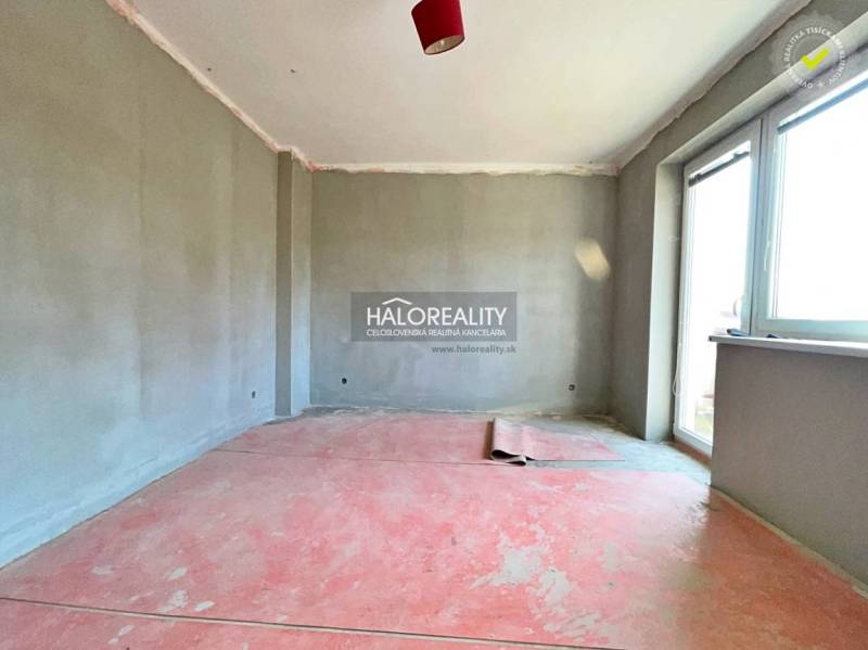 A room in a family house with unplastered walls and a large window.