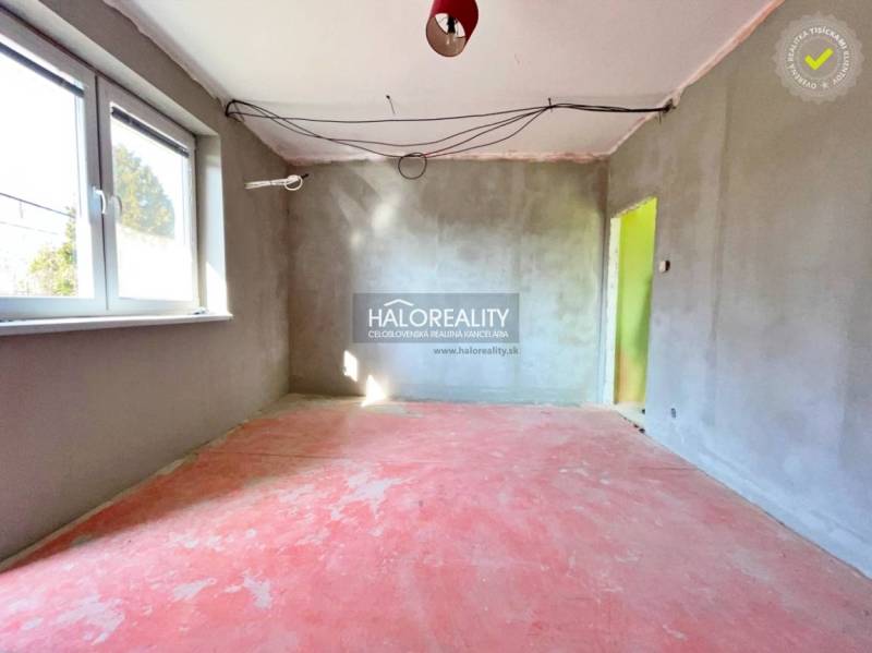 Interior of a family house under construction with a concrete floor and plastered walls.