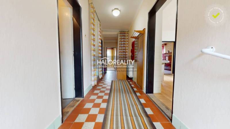 A hallway in a family house with a carpet and colorful patterned curtains.