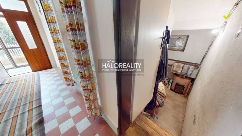 The hallway of a family house with a tiled floor and a staircase.