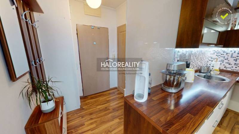 A kitchen of a 2-room apartment with a wooden decor floor and practical accessories.
