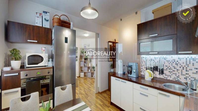 Kitchen of a 2-room apartment with a stainless steel refrigerator and wood-patterned flooring.