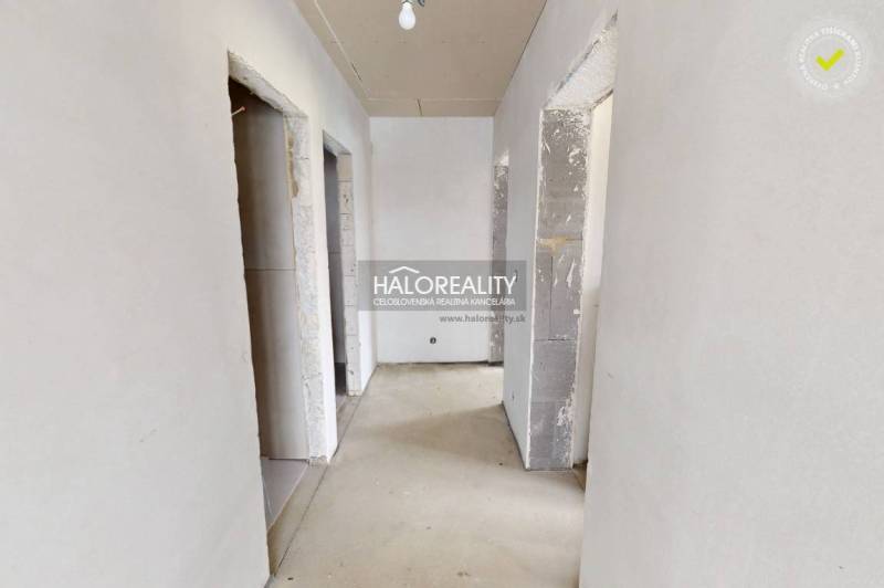A hallway in an office with unfinished walls and floor, suitable for interior renovation.