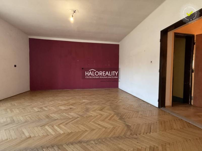 A room in a family house with a wooden decor floor and a purple wall.