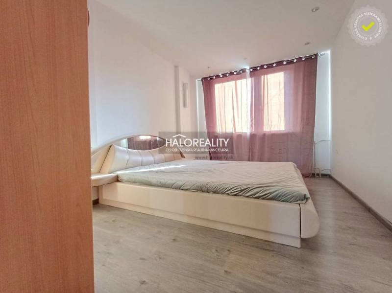 Bedroom with a comfortable bed in a 3-room apartment, floor with wood decor, curtains.