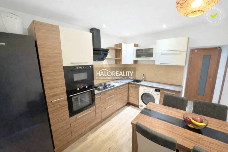 A kitchen in a 3-room apartment with wood decor, appliances, and a dining table.