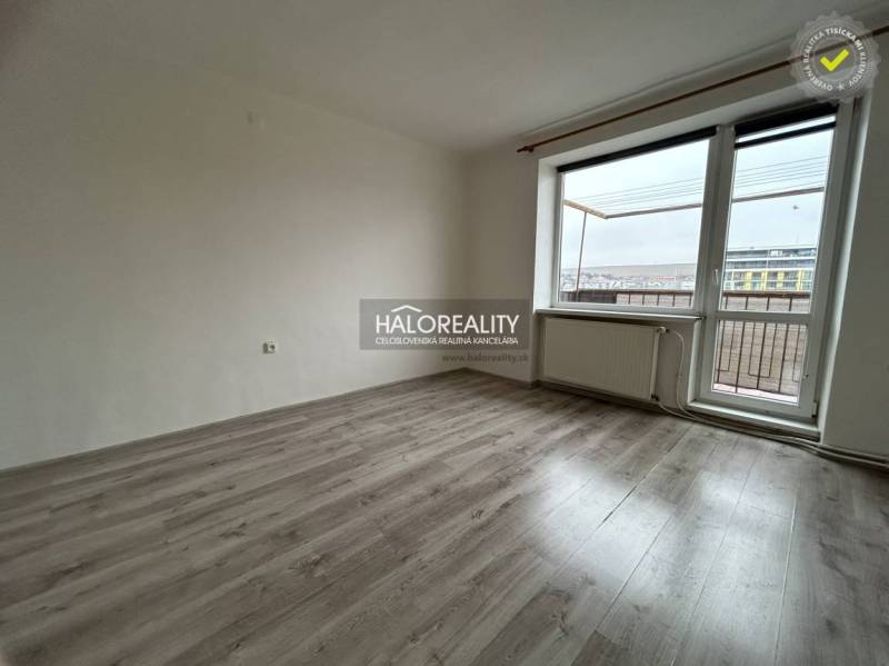 A room in a 2-room apartment with a wooden decor floor and a balcony.