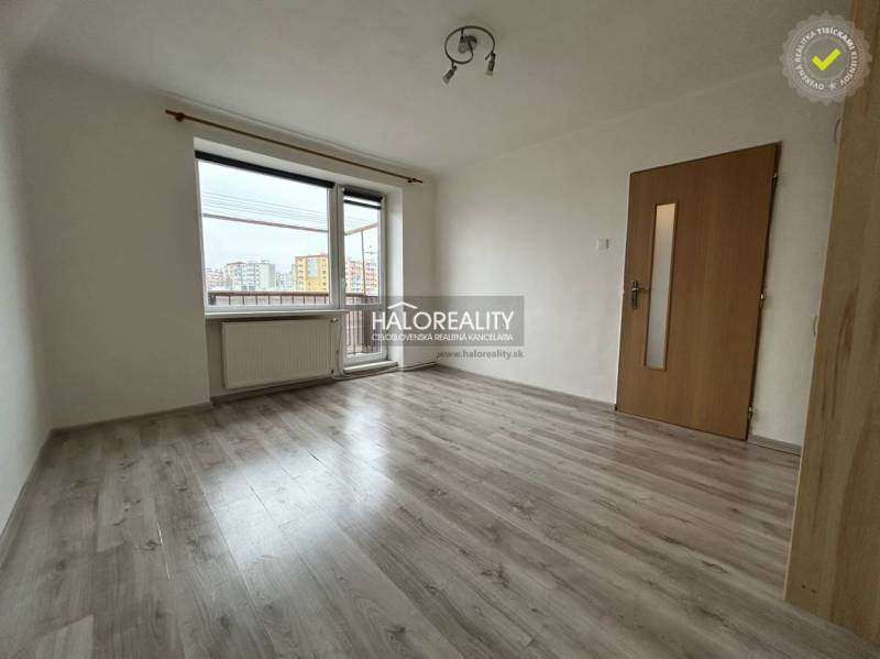 A spacious room with a wooden decor floor and a balcony in a 2-room apartment.