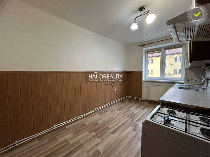 A kitchen with a wood-patterned floor in a 2-room apartment, a bright space with a window.