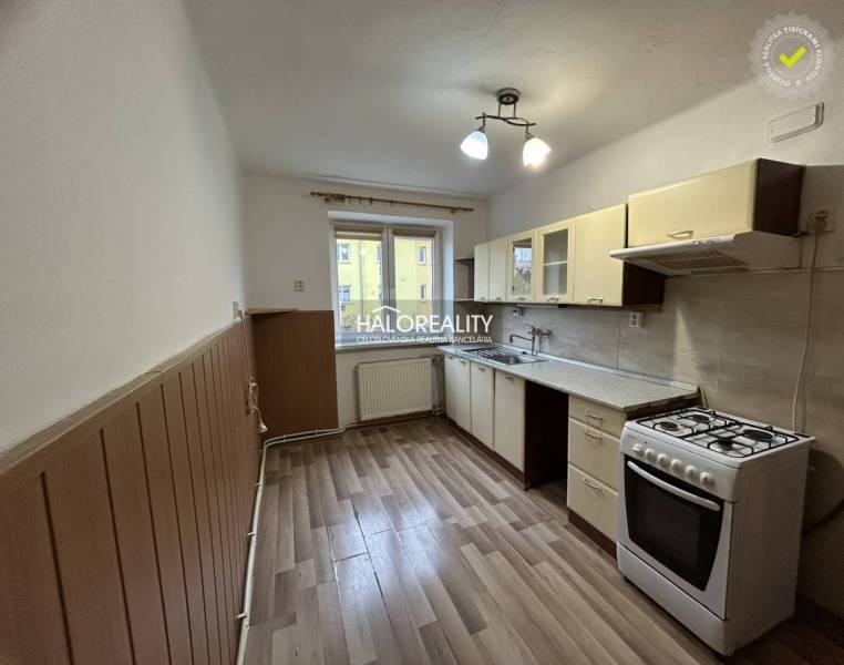 A kitchen in a 2-room apartment with a gas stove and a floor with a wooden decor.