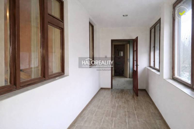 A hallway in a family house with a wooden decor floor and large windows.