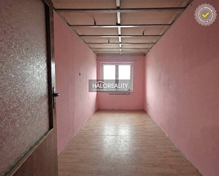 A narrow room with light pink walls and a wooden decor floor in a family house.