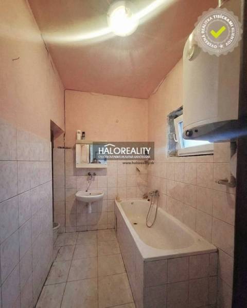 Bathroom with a bathtub and sink in a family house with white tiles.