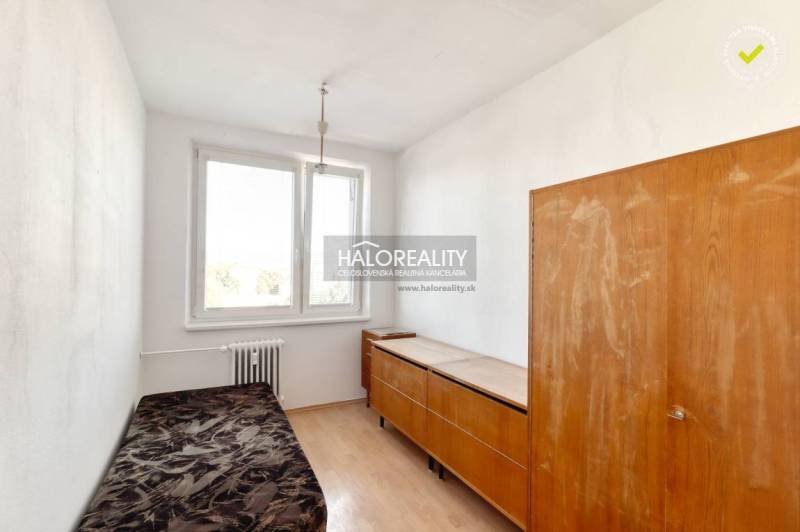 A room in a 2-room apartment with a wooden decor floor and simple furniture.