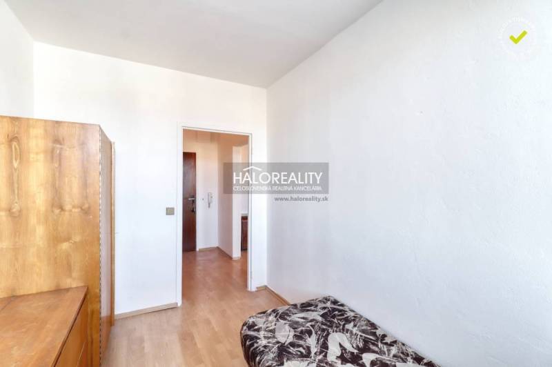 A room in a 2-room apartment with a bed, a wardrobe, and a floor with a wooden decor.