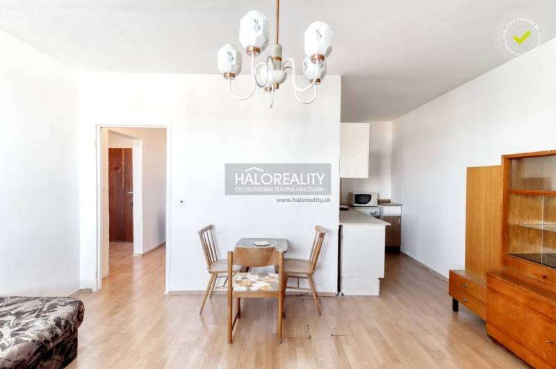 Dining table with chairs in a 2-room apartment, floor with wooden decor, white interior.