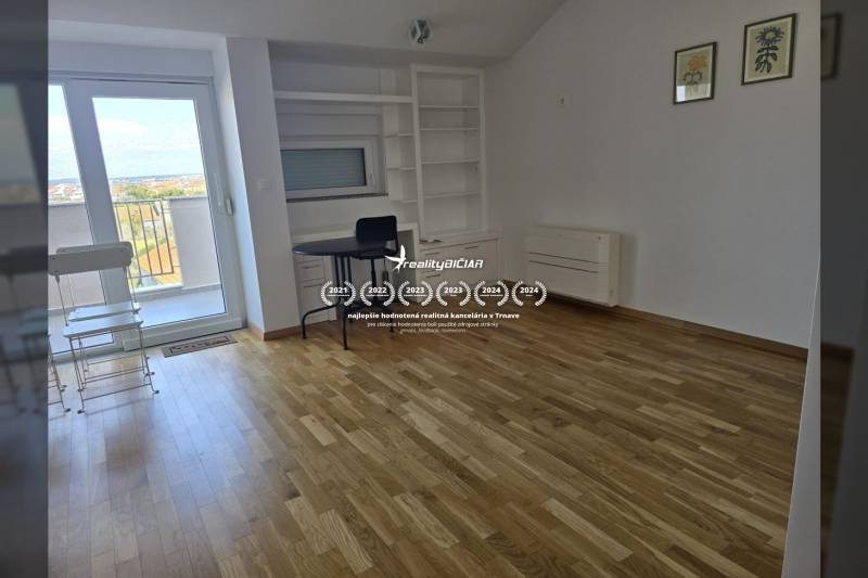 Interior of a vacation apartment with wood-patterned flooring, a table, and built-in shelves.