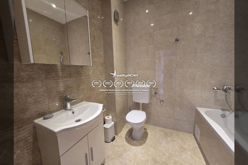 A bathroom in a holiday apartment with sanitary ware and tiles in neutral tones.