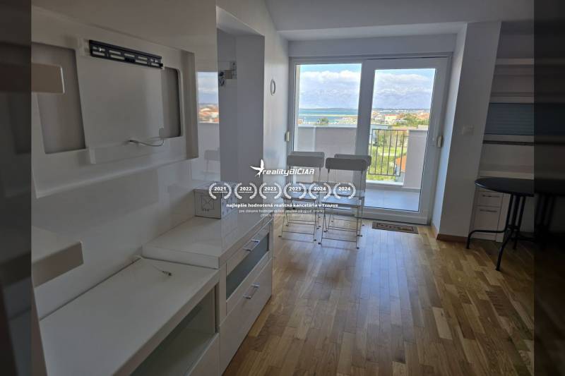 Recreational apartment with wood-patterned flooring, balcony with sea view.