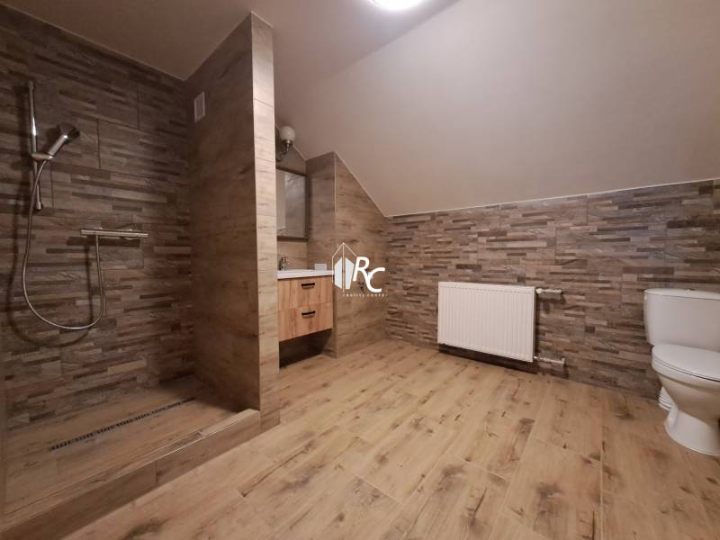 Bathroom with toilet and shower, wooden decor flooring, 3-room apartment.