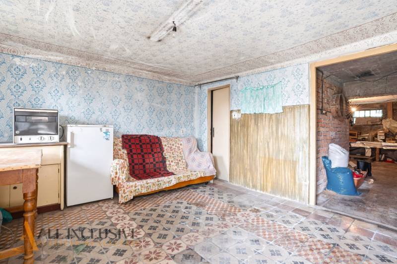 A room in a family house with a sofa, refrigerator, and stove, decorative patterned walls and floor.