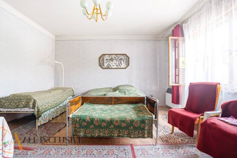 A room in a family house with two beds, carpets, and armchairs under the window.