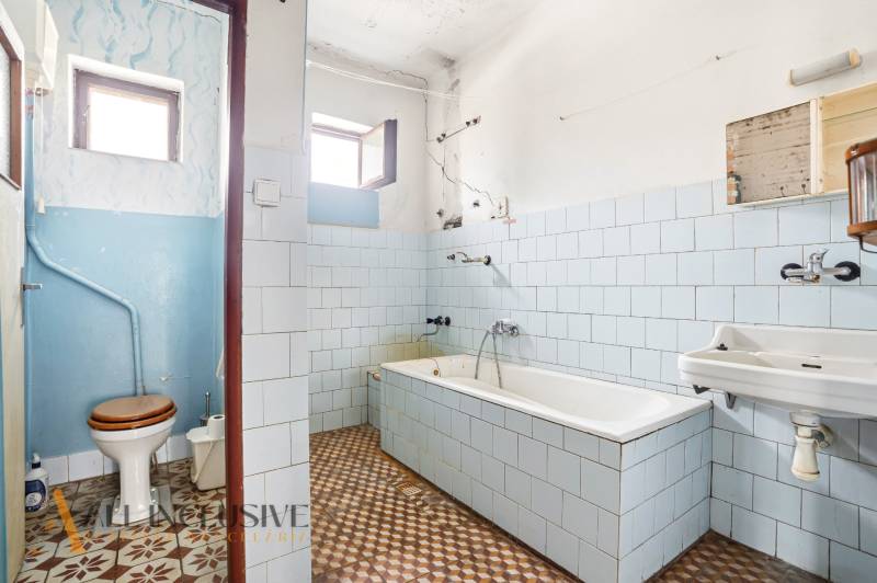 Bathroom with a bathtub, toilet, sink, and window in a family house.
